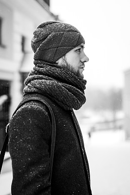 户外肖像英俊的男子在灰色大衣。时尚照片。美丽冬天下雪的风格。黑色和白色图片下载