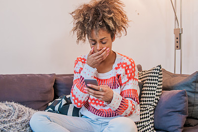 年轻的非洲女人坐在客厅里发短信。图片下载