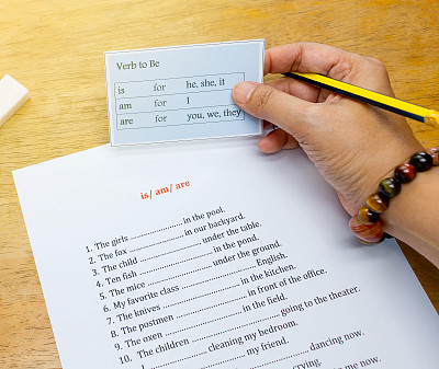 手拿英语卡片放在棕色的木桌上图片下载