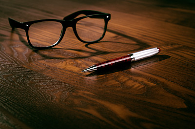 玻璃杯和笔放在一张天然木制的桌子上。办公室。在办公室工作的概念和配件。图片下载