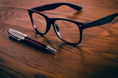 玻璃杯和笔放在一张天然木制的桌子上。办公室。在办公室工作的概念和配件。图片下载