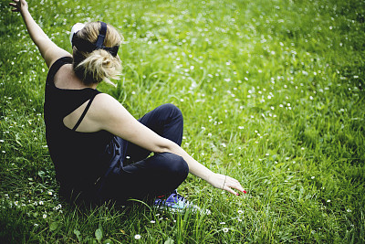 女性坐在草地上，使用虚拟盒子进行移动图片下载