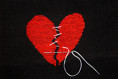破碎的心在黑色的织物上绣着红色的线。图片下载
