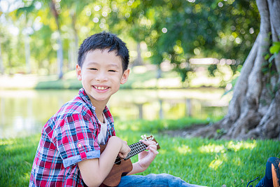 在公园里玩尤克里里的男孩图片下载
