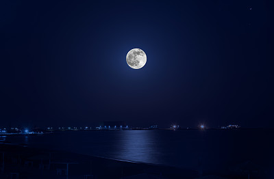 满月的照片在黑色的天空与海面上的反射图片下载