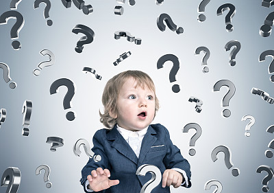 小男孩和灰色墙上的问号图片下载