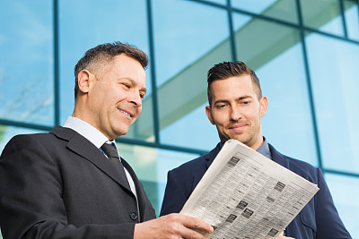 两个正在看报纸的商人图片下载