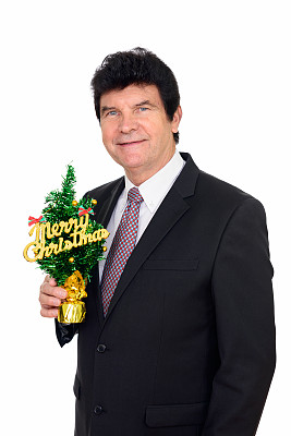 快乐成熟的商人微笑着，抱着圣诞树快乐图片下载