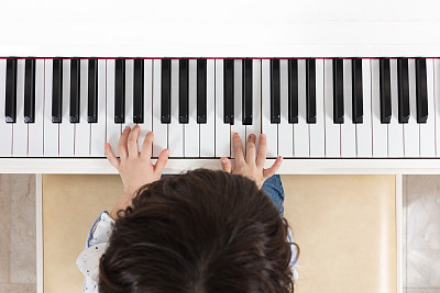 亚洲华人小男孩弹钢琴的鸟瞰图图片下载
