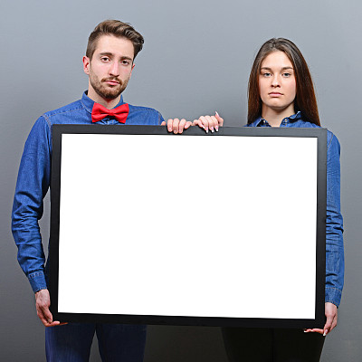 一对严肃的夫妇在灰色背景下拿着空白板图片下载