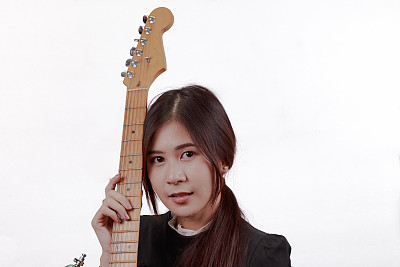 年轻的亚洲女人喜欢弹吉他的肖像，孤立在白色的背景。图片下载