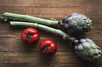 木色背景上有洋蓟和西红柿，健康食品和配料，蔬菜图片下载