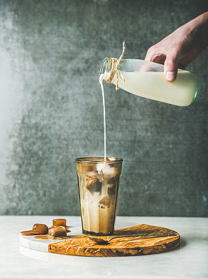 男子的手倒牛奶冰拿铁焦糖咖啡鸡尾酒图片下载