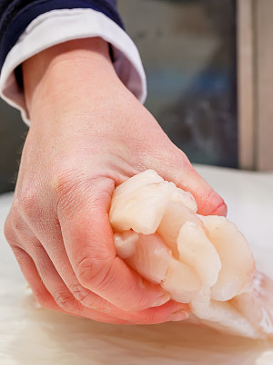 在市场上，鱼贩子手里拿着一块新鲜的鱼图片下载