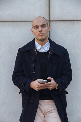 年轻英俊的秃顶商人拿着智能手机。图片下载