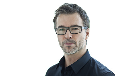 看着相机的成熟严肃的商人。孤立在白色素材图片