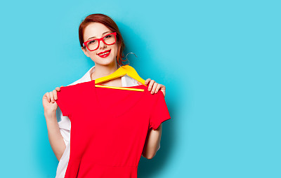 美丽的年轻女子的照片衣架上的衬衫在美妙的蓝色工作室背景图片下载