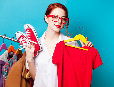 美丽的年轻女人的照片与衬衫衣架和刑警鞋附近的衣服在美妙的蓝色背景图片下载