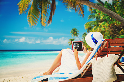 在热带海滩上拿着触摸板的女人图片下载