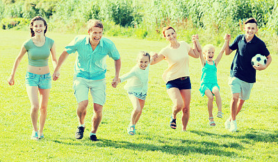 微笑的父母和四个孩子在绿色的草坪上图片下载