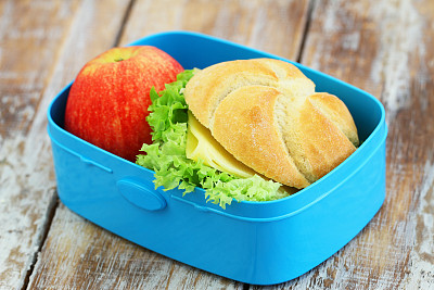 午餐盒，里面有奶酪三明治和木头上的红苹果图片下载