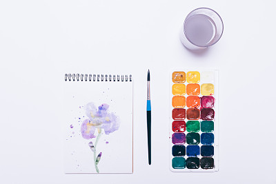 水彩颜料，刷子，画蓝色的花和一个玻璃与水在白色的背景图片下载