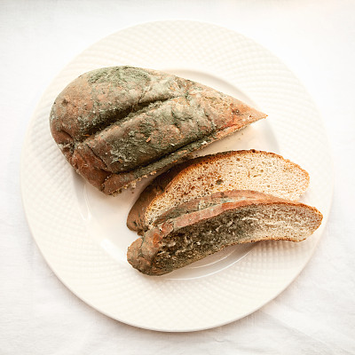 腐烂的切好的面包上覆盖着绿色霉菌图片下载