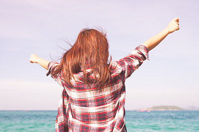 女人放松在海滩享受夏天的自由与开放的手臂和头发在水海边的风。亚洲女孩在夏季旅游假期假期外。复古效果风格的图片。图片下载