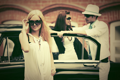 快乐年轻时尚的金发女人戴着太阳镜旁边的复古车图片下载