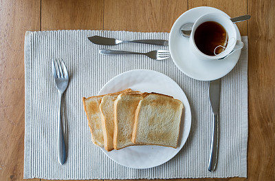桌布将面包切片放在白色的盘子和茶杯上图片下载