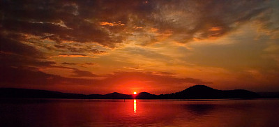 生动的多云深红色日出与水的倒影。图片下载