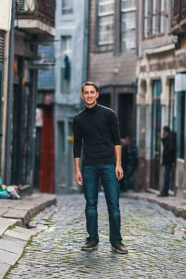 英俊的年轻人站在市中心的大街上。图片下载