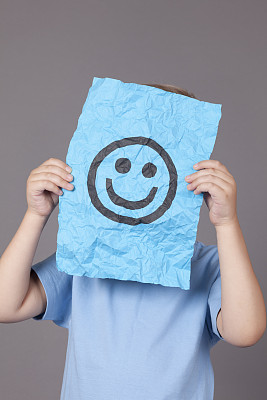 小男孩拿着一张带笑脸的纸图片下载