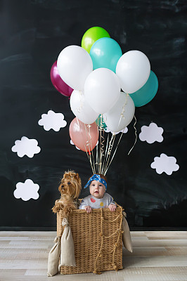 小女孩和宠物狗坐在气球篮子里图片下载