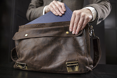 穿着夹克的老师从一个旧皮包里拿了一本书图片下载