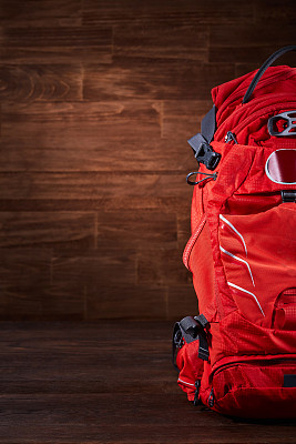 木制背景上的大橙色旅游背包。图片下载