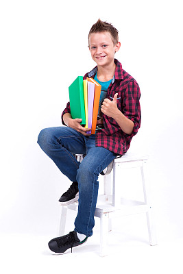 一个快乐的欧式男生穿着衬衫和牛仔裤坐在椅子上拿着一本书，照片由景深拍摄图片下载