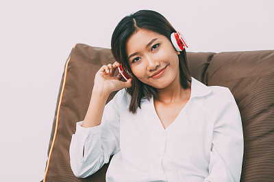 Content Asian Woman in耳机on Cushion图片下载