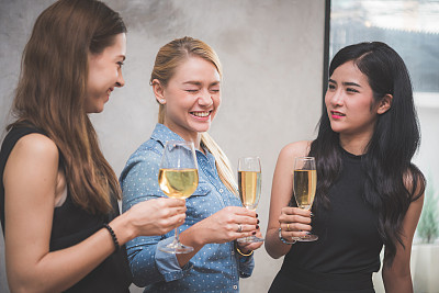 三个漂亮的年轻女人一边喝着酒和香槟一边谈笑风生图片下载