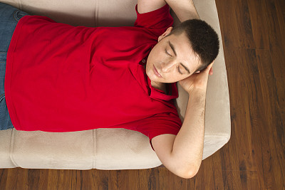 在舒适的沙发上睡觉的年轻人图片下载