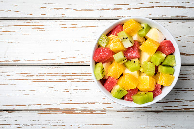 新鲜的水果沙拉放在一张旧的白色木桌上素材图片
