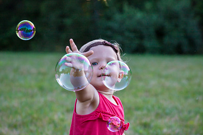 蹒跚学步的小女孩伸手去拿肥皂泡图片下载