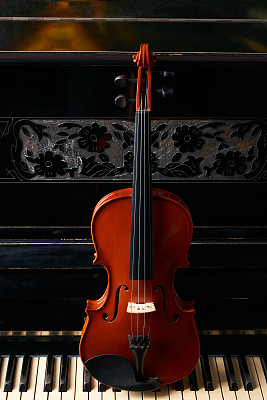 古典音乐中的弦乐器小提琴在钢琴琴键上。图片下载