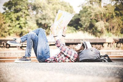 旅行者女人背着背包拿着地图，等着火车。图片下载