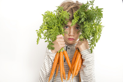 一个悲伤的小男孩的肖像，白色的背景上有胡萝卜束图片下载