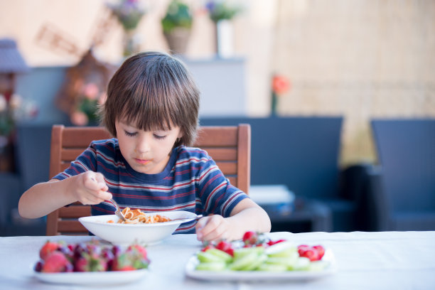 可爱的孩子，学前班的小男孩，午餐在户外吃意大利面图片下载