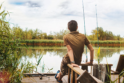 拿着鱼竿的男孩。男孩在钓鱼。后视图图片下载