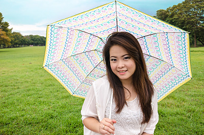 草地上美丽的年轻女子，手里拿着可爱的雨伞图片下载