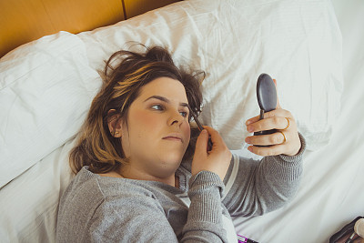 一个女人躺在床上化妆图片下载