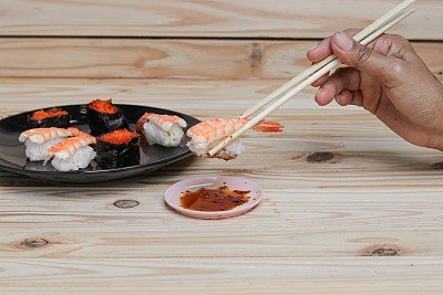 手拿寿司筷子放在一张黑色的木桌上图片下载
